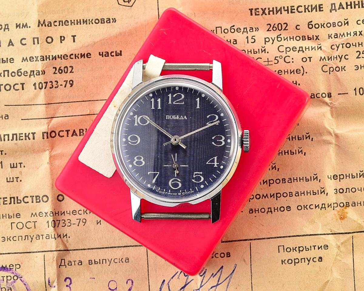 Mechanical wristwatch in box displayed on vintage papers, showcasing TIME CAPSULE: Mechanical POBEDA watch NOS.
