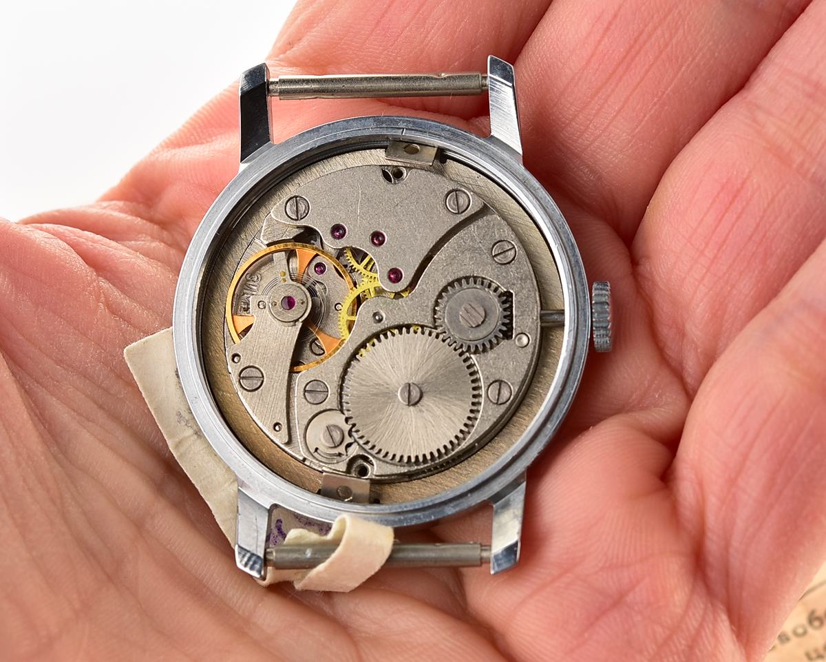 Close-up of a Pobeda mechanical wristwatch movement in hand, showcasing inner watch gears and mechanisms.