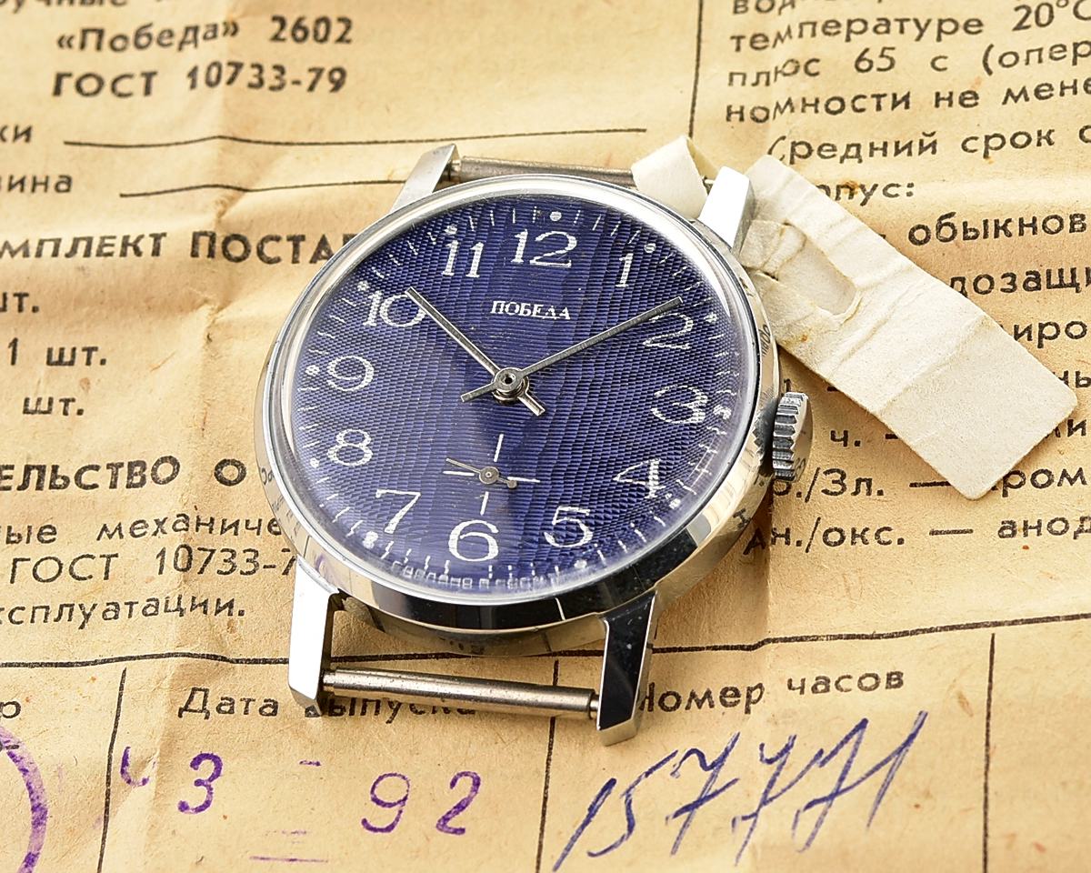 Mechanical wristwatch Pobeda displayed on vintage documents with original tag, TIME CAPSULE NOS in box.